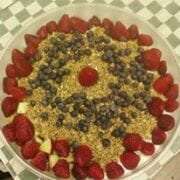 A bowl of fresh cut melon and berries topped with yogurt and granola.