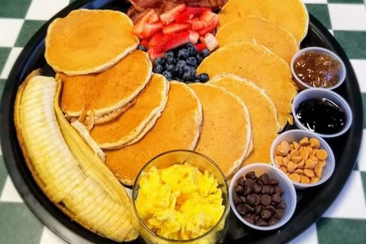 A plate of pancakes beside eggs and a side of hash browns.