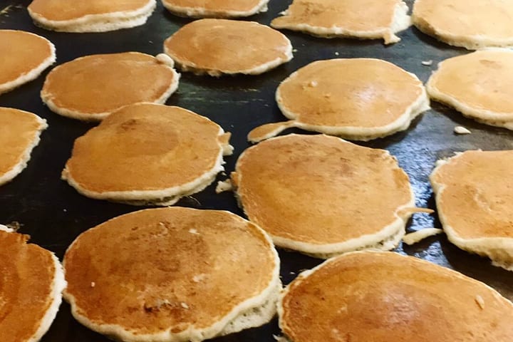 Pancakes cooking on the flat top griddle.