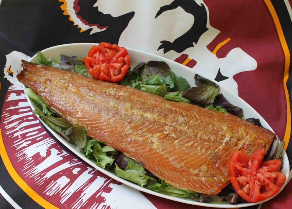 A catering platter of smoked salmon with crackers, lettuce and garnish.