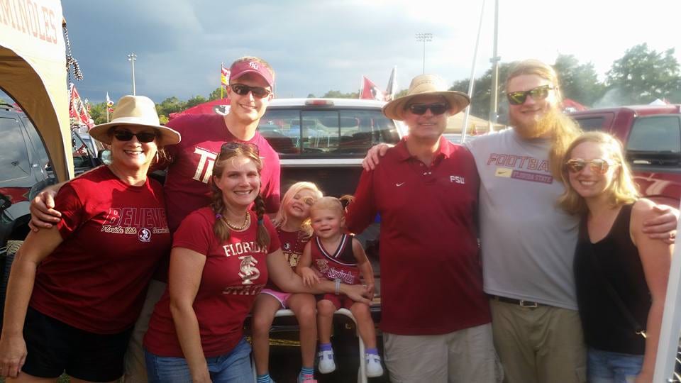 Eight members of a family in Florida State shirts and hats standing together at a tailgate.